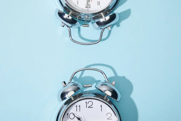 Vista superior de los relojes de alarma clásicos sobre fondo azul - foto de stock