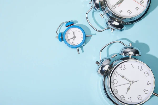 Vista superior de los relojes de alarma clásicos sobre fondo azul - foto de stock