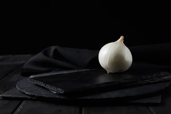 Whole white onion on black chopping boards isolated on black — Stock Photo