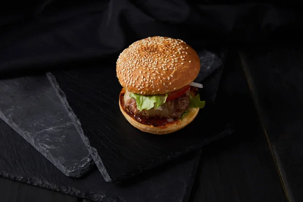 Vista de ángulo alto de hamburguesa en la superficie de madera negro - foto de stock