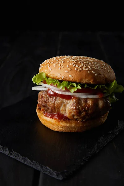 Tasty burger on wooden surface isolated on black — Stock Photo