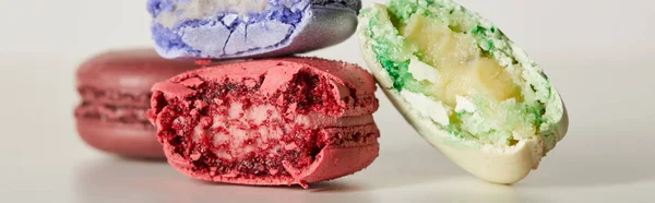 Selective focus of assorted delicious bitten colorful french macaroons on white background, panoramic shot — Stock Photo