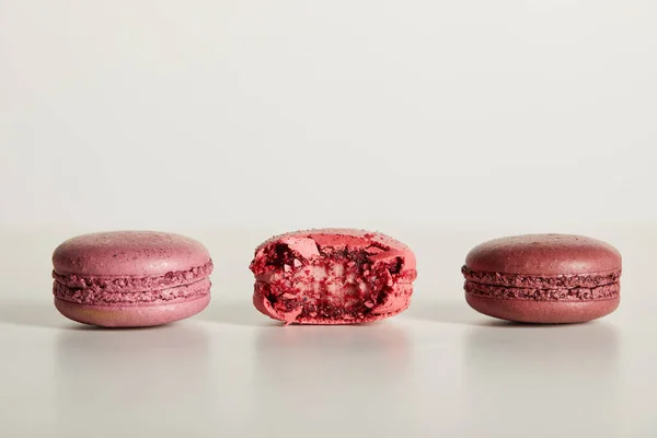 Delicious whole and one bitten red french macaroons on white background — Stock Photo