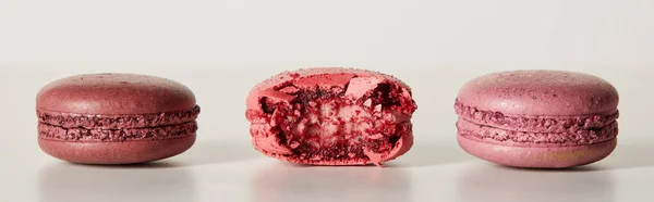 Delicioso inteiro e um macaroons francês vermelho mordido no fundo branco, tiro panorâmico — Fotografia de Stock