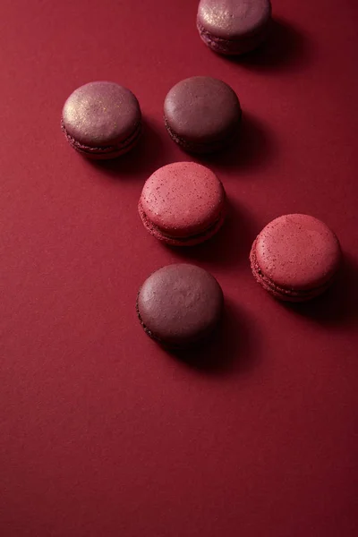 Délicieux macarons français colorés sur fond rouge — Photo de stock