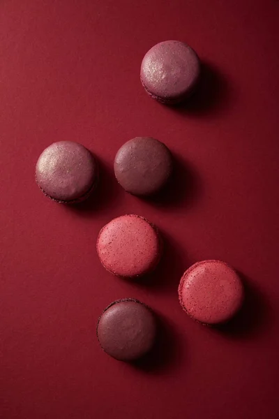 Vista superior de deliciosos macaroons franceses coloridos no fundo vermelho — Fotografia de Stock