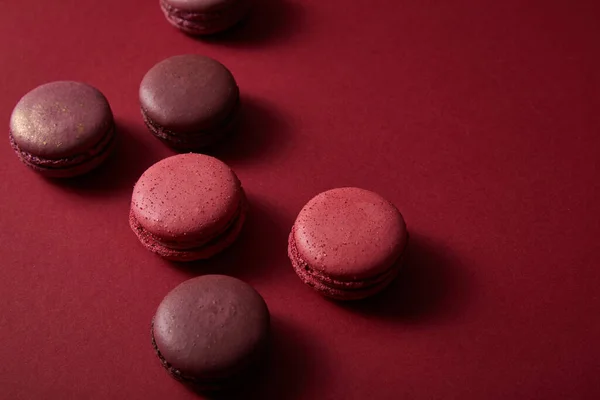 Délicieux macarons français colorés sur fond rouge — Photo de stock