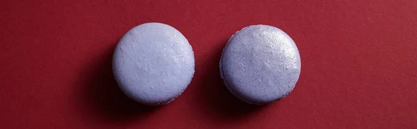 Vue de dessus de délicieux macarons français violets et colorés sur fond rouge, panoramique — Photo de stock