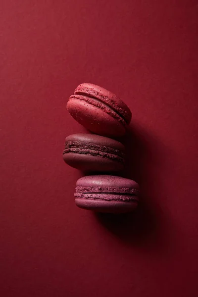 Vue de dessus de délicieux macarons français colorés sur fond rouge — Photo de stock