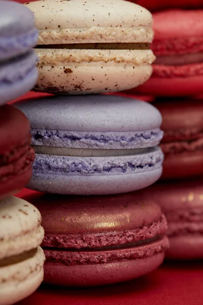 Pila di deliziosi macaron francesi colorati assortiti su sfondo rosso — Foto stock