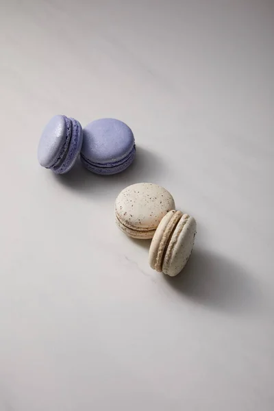 Assorted delicious violet and white  french macaroons on grey background — Stock Photo