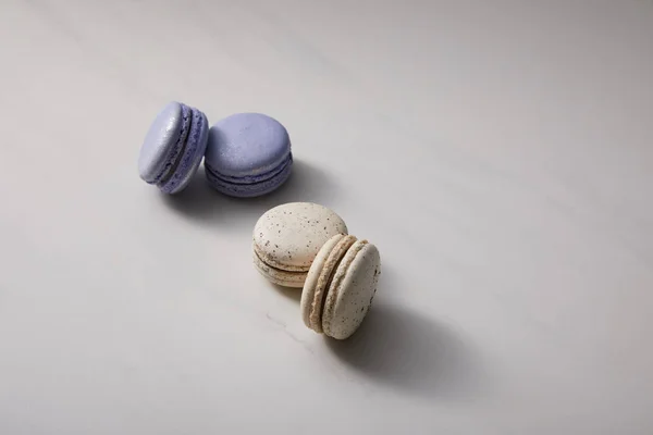 Surtido delicioso violeta y macarrones franceses blancos sobre fondo gris - foto de stock