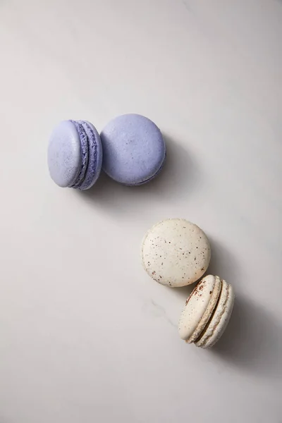 Vista dall'alto di deliziosi macaron viola assortiti e bianchi francesi su sfondo grigio — Foto stock