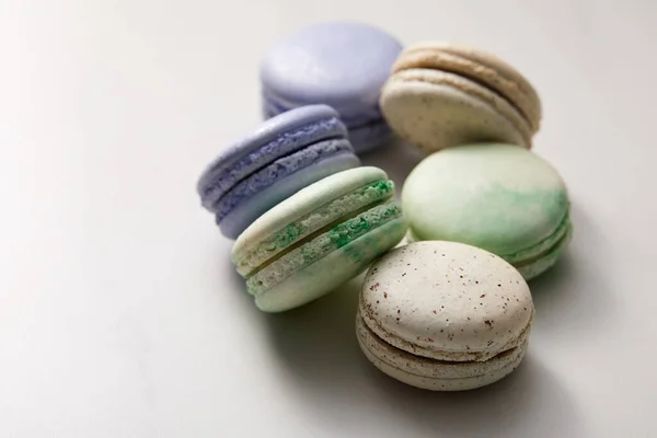Close up view of assorted delicious green, violet and yellow french macaroons on grey background — Stock Photo
