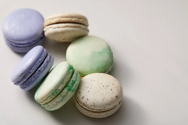 Vista de cerca de una variedad de deliciosos macarrones verdes, violetas y amarillos franceses sobre fondo gris - foto de stock