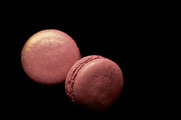 Vue de dessus des macarons français rose brillant isolés sur noir — Photo de stock