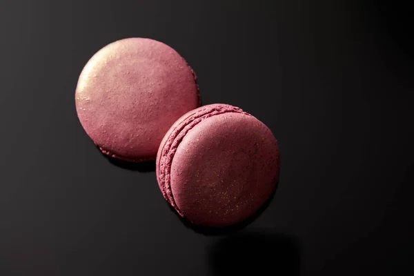 Top view of shiny pink french macaroons on black background — Stock Photo