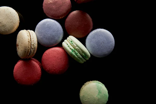 Vista superior de una variedad de deliciosos macarrones franceses coloridos aislados en negro - foto de stock