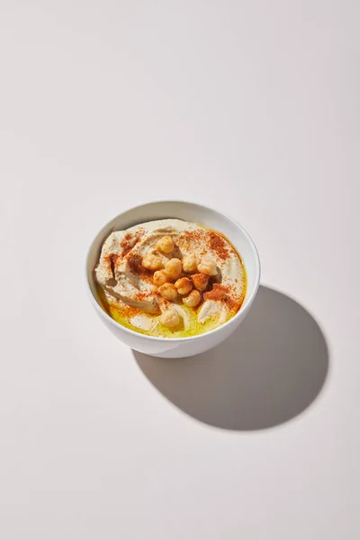 Hummus with chickpea, spices and olive oil in bowl on grey background — Stock Photo
