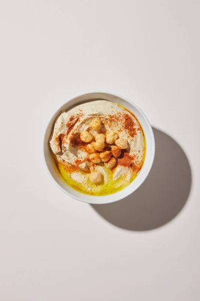 Vista superior da tigela com delicioso hummus no fundo cinza — Fotografia de Stock