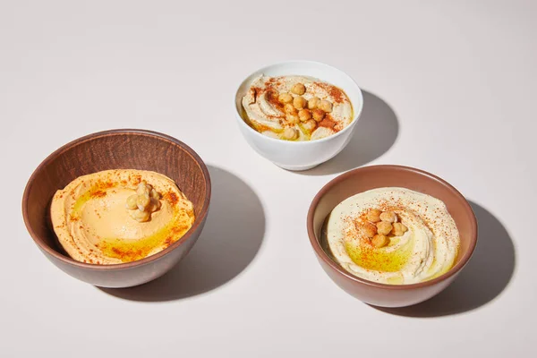 Tigelas com delicioso hummus em fundo cinza — Fotografia de Stock