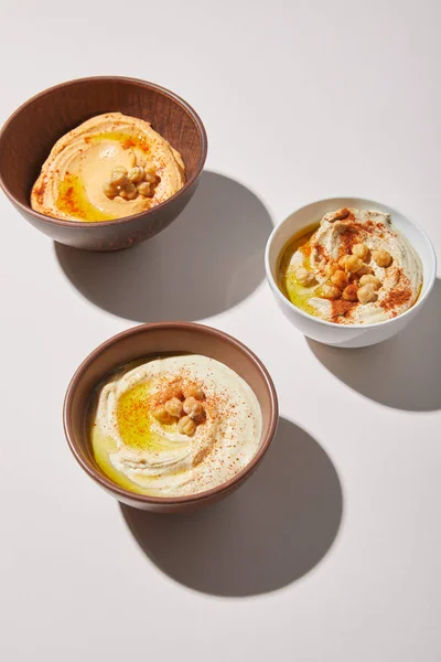 Bols avec houmous délicieux et pois chiches sur fond gris — Photo de stock