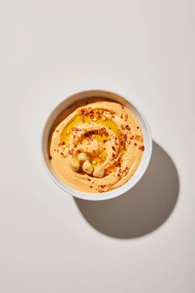 Top view of bowl with delicious hummus on grey background — Stock Photo