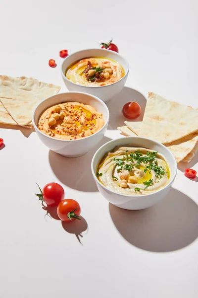 Bol avec houmous délicieux, tomates cerises mûres et pain pita sur fond gris — Photo de stock