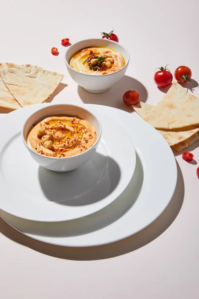 Assiettes et bols avec houmous, légumes et pain pita sur fond gris — Photo de stock