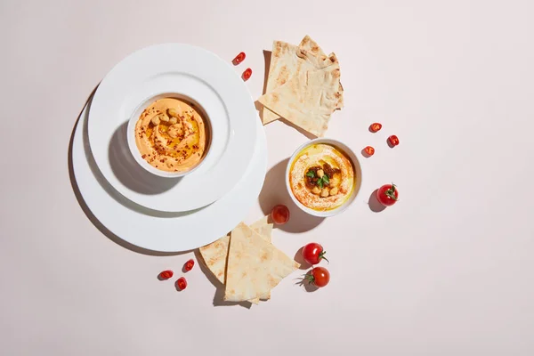 Vista superior de pratos e tigelas com hummus, legumes e pão pita em cinza — Fotografia de Stock