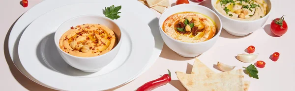 Plates and bowls with hummus, vegetables and pita bread on grey, panoramic shot — Stock Photo