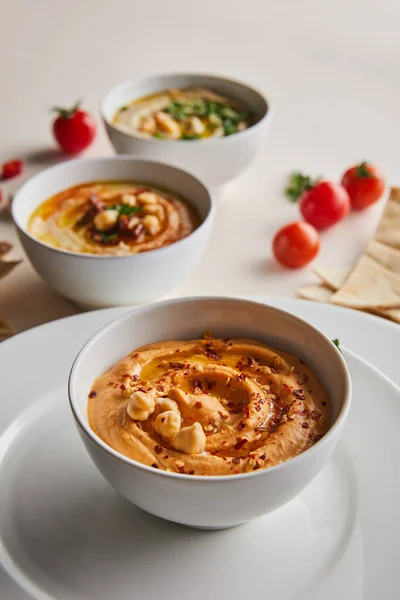 Close up view of plates and delicious hummus with chickpea and spices in bowls — Stock Photo