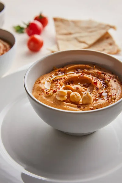 Close up view of bowl with tasty hummus on plate on grey background — Stock Photo