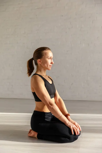 Donna attraente che fa esercizio seiza sul pavimento in studio di yoga — Foto stock