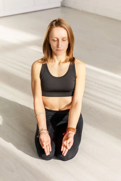 Atractiva mujer con los ojos cerrados meditando mientras está sentada en el suelo - foto de stock