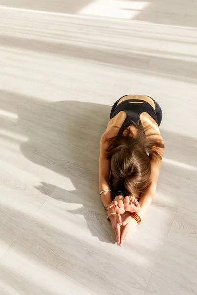 Молода і гнучка жінка практикує йогу на підлозі — стокове фото