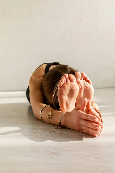 Donna flessibile con stretching a piedi nudi sul pavimento — Foto stock