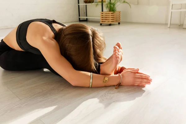 Mujer flexible con pies descalzos estirándose en piso en estudio de yoga — Stock Photo