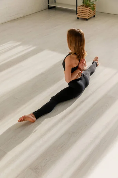 Donna in posa di preghiera inversa facendo spago stretching sul pavimento — Foto stock