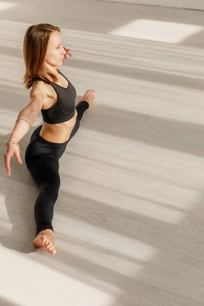 Attractive woman with outstretched hands doing twine stretching on floor — Stock Photo