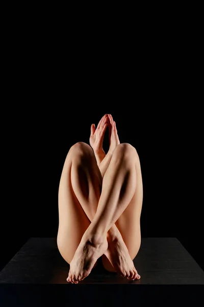 Woman with crossed legs practicing yoga isolated on black — Stock Photo