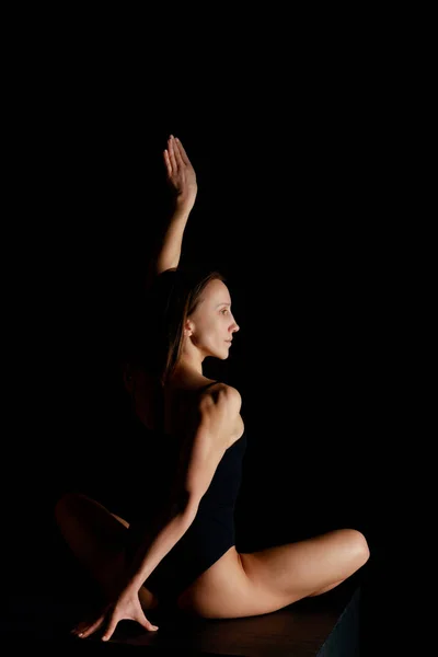 Jolie femme en pose de lotus pratiquant le yoga isolé sur noir — Photo de stock