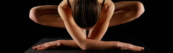 Панорамний знімок спортивної жінки, що практикує йогу ізольовано на чорному — стокове фото