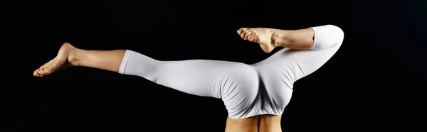 Plano panorámico de mujer joven en ropa deportiva blanca haciendo soporte de mano aislado en negro - foto de stock