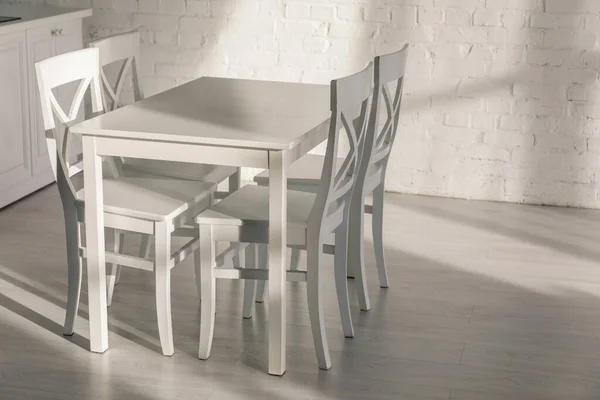 Chaises près de la table et mur de briques dans la cuisine moderne — Photo de stock