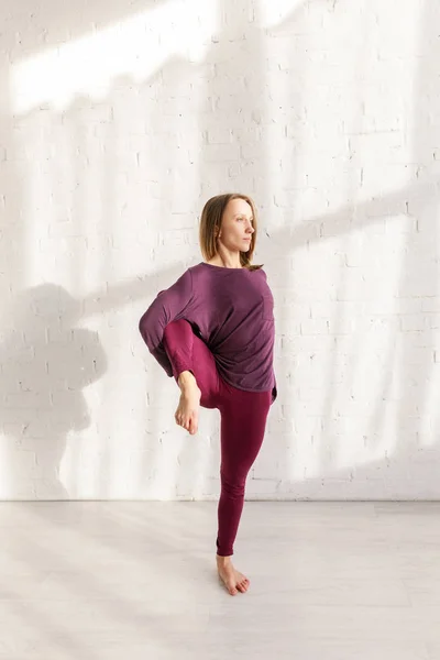 Jeune femme en vêtements de sport faisant de l'exercice dans un studio de yoga — Photo de stock