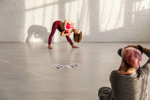 Selective focus of sportive woman with barefoot doing yoga exercise near photographer — Stock Photo