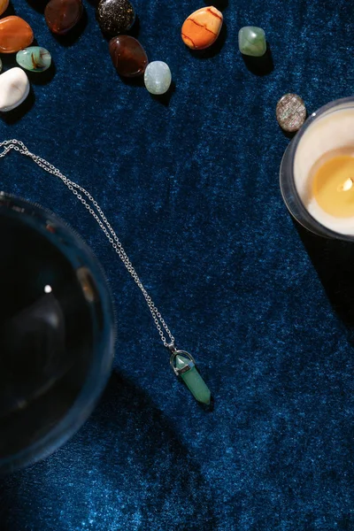 Top view of crystal ball, candle and fortune telling stones on dark blue velour cloth — Stock Photo