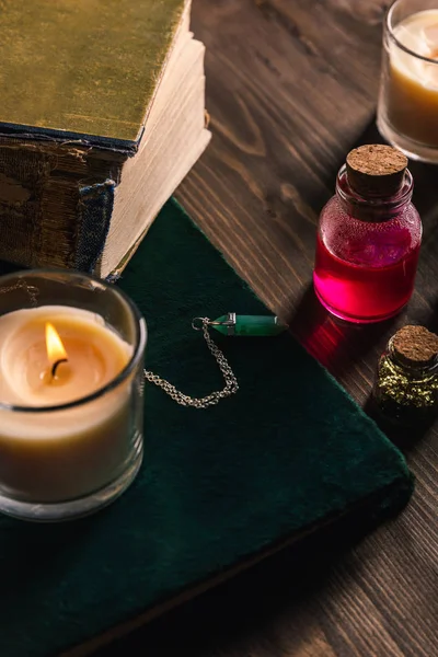 Банки с травами и настойкой, книги и свечи на деревянном фоне — стоковое фото