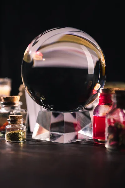 Crystal ball with jars of dried herbs and tincture isolated on black — Stock Photo